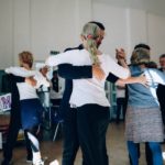 A group of adults practicing ballroom dancing in a sunlit indoor studio, capturing elegance and grace.