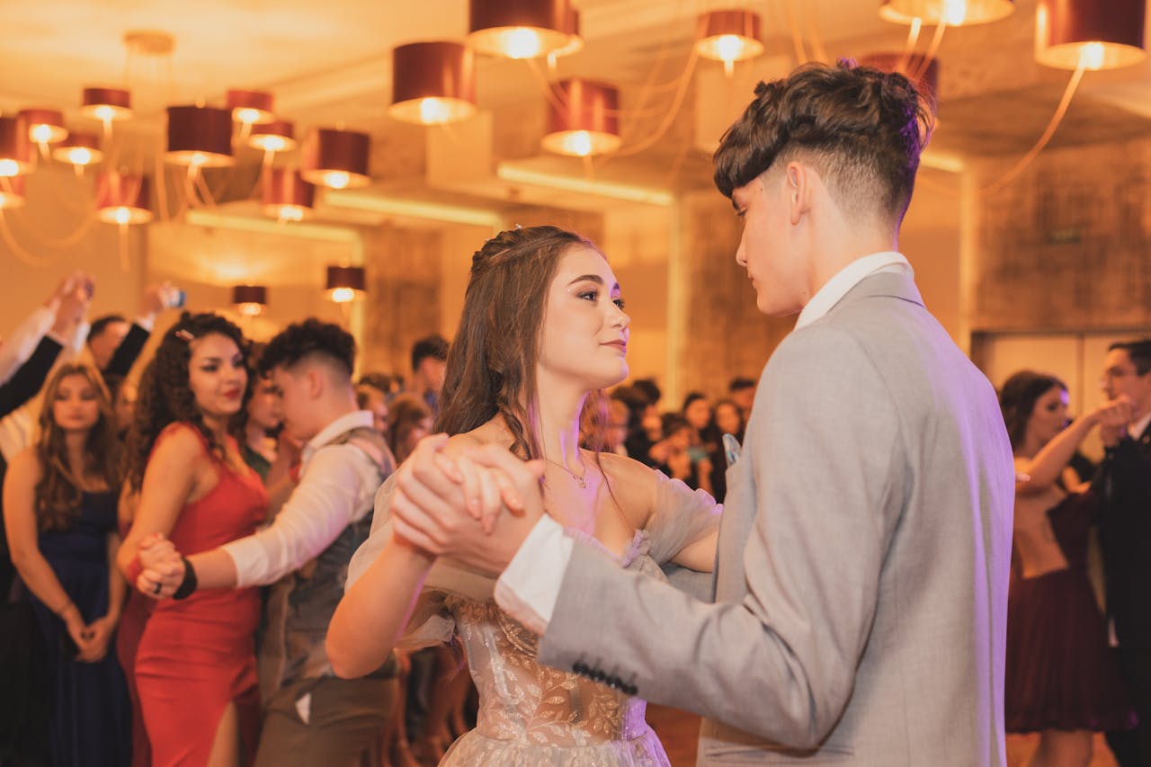 A couple dancing gracefully at a formal party with elegant lighting.