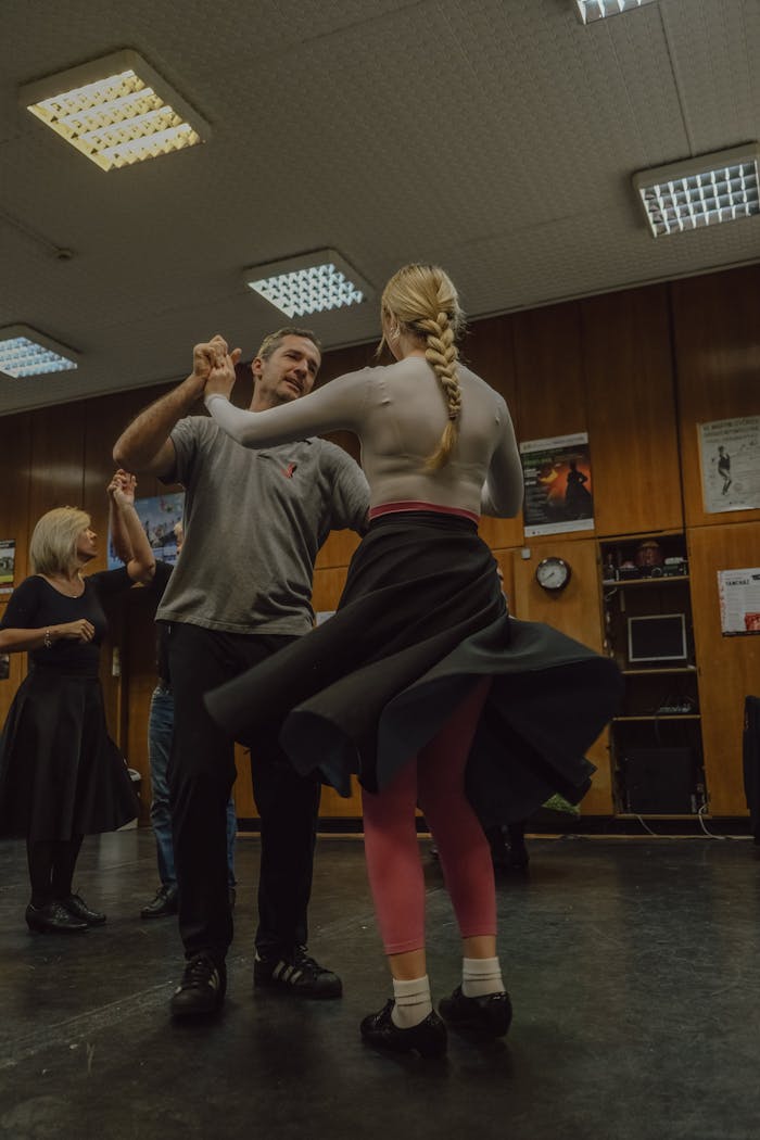 A couple practicing dance moves together in a well-lit studio environment.